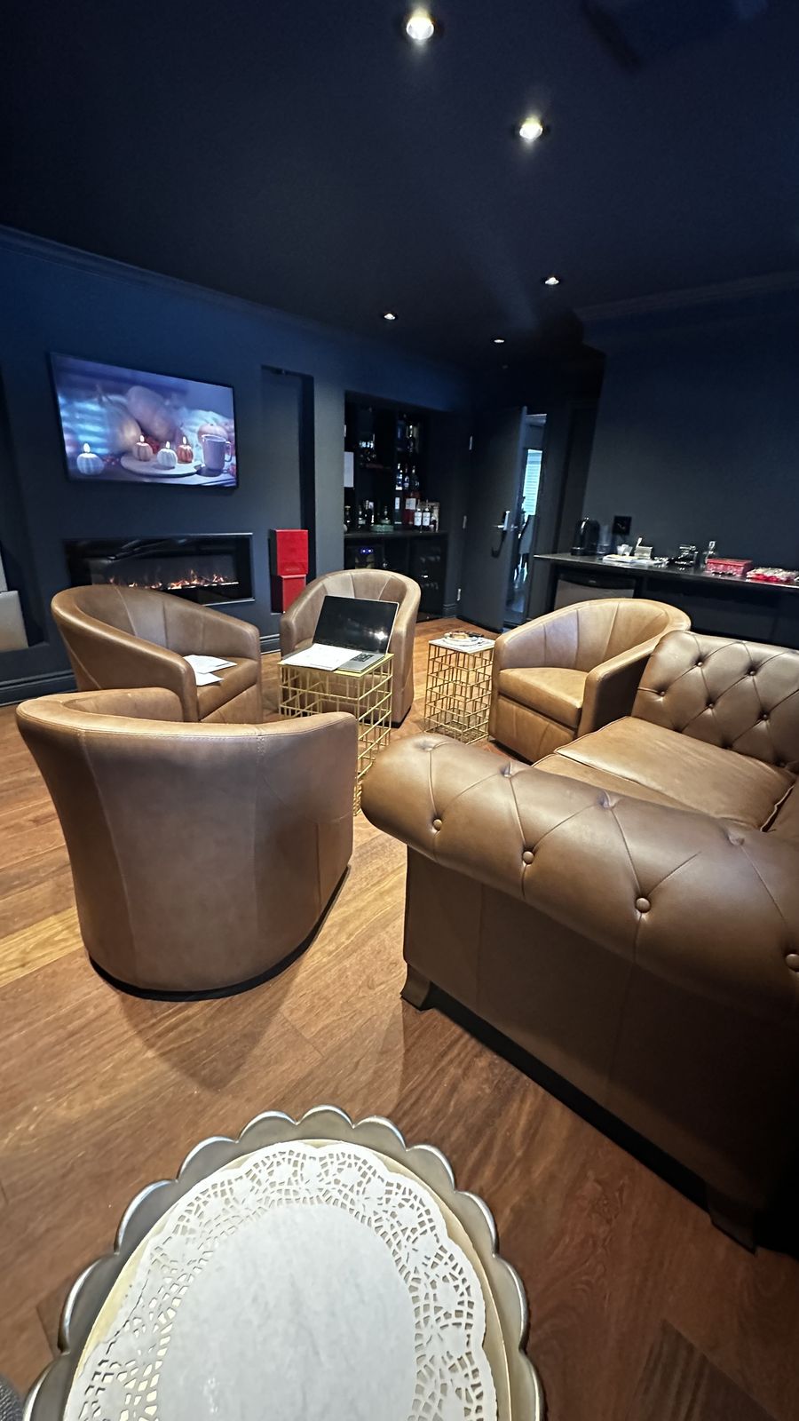 A high-end basement lounge with recessed lighting, leather seating and a linear fireplace