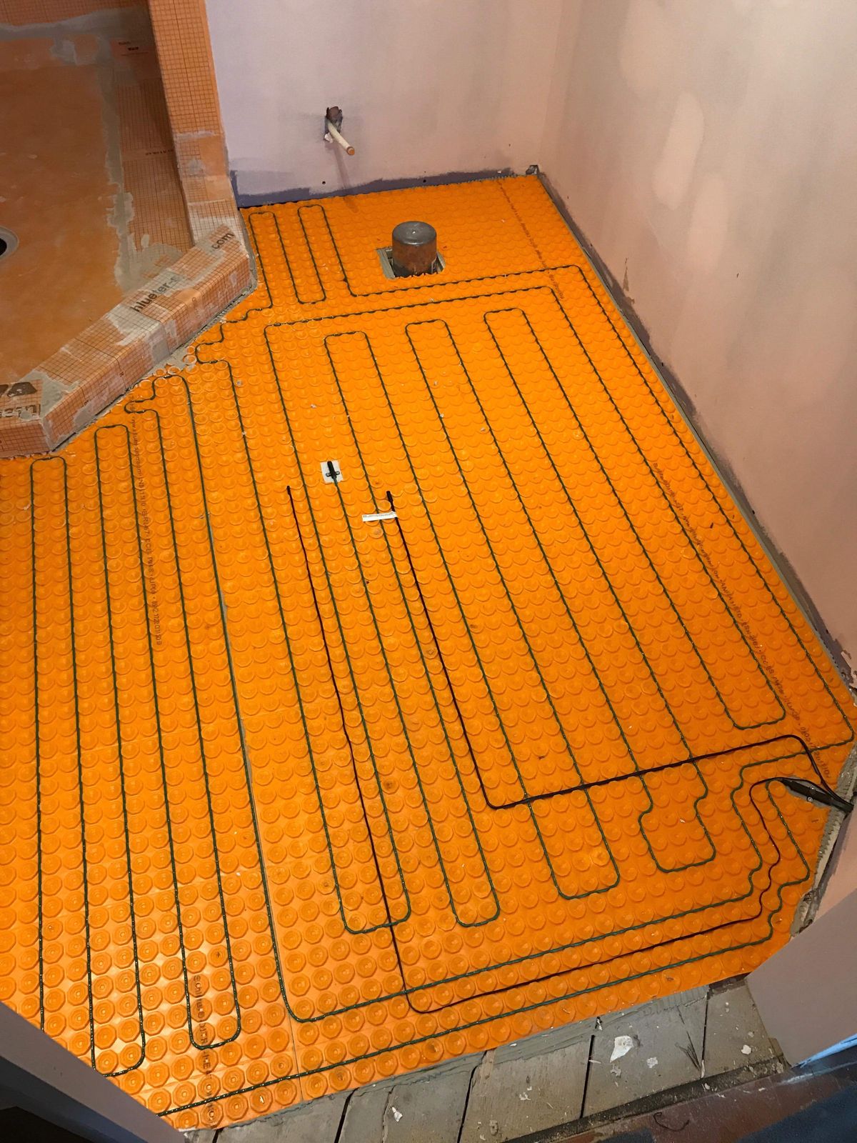Un plancher de salle de bain avec câble chauffant posé en boucles serrées et régulières