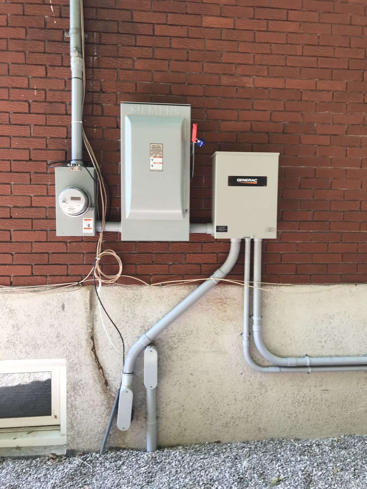 A new service entrance on a brick home, with a disconnect switch, meter and transfer switch