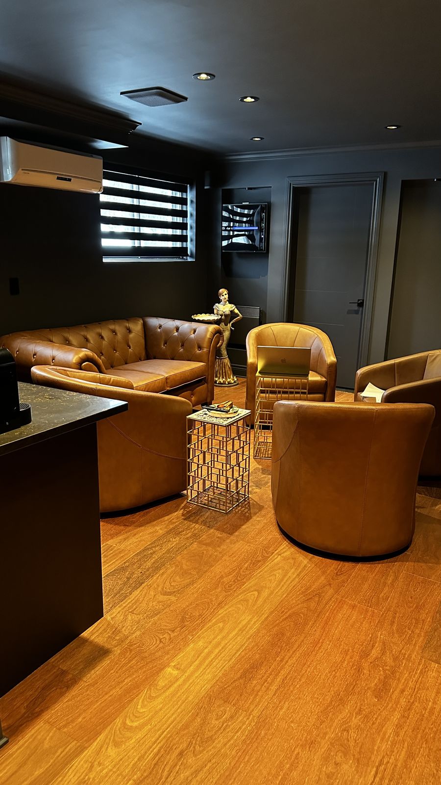 A warm, high-end home lounge with leather seating, hardwood floors and recessed lighting