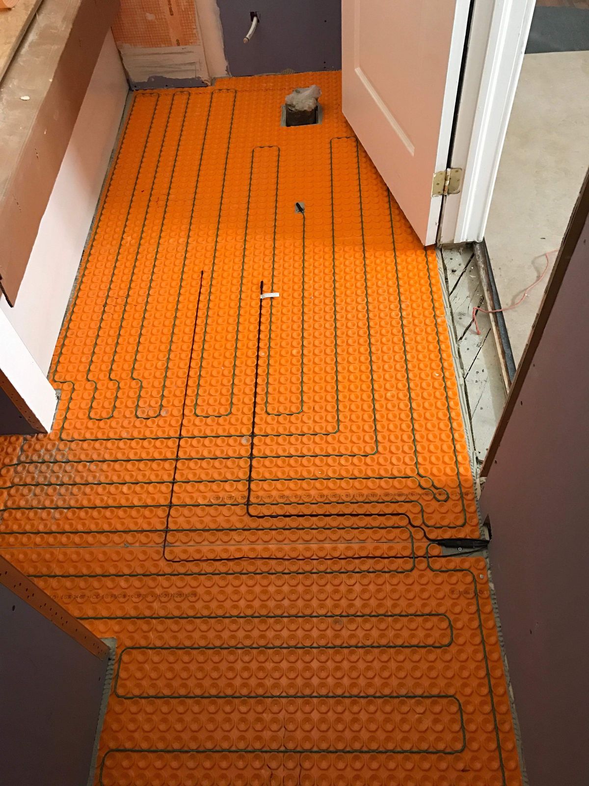 Câble chauffant posé en boucles régulières sur le plancher d’une pièce