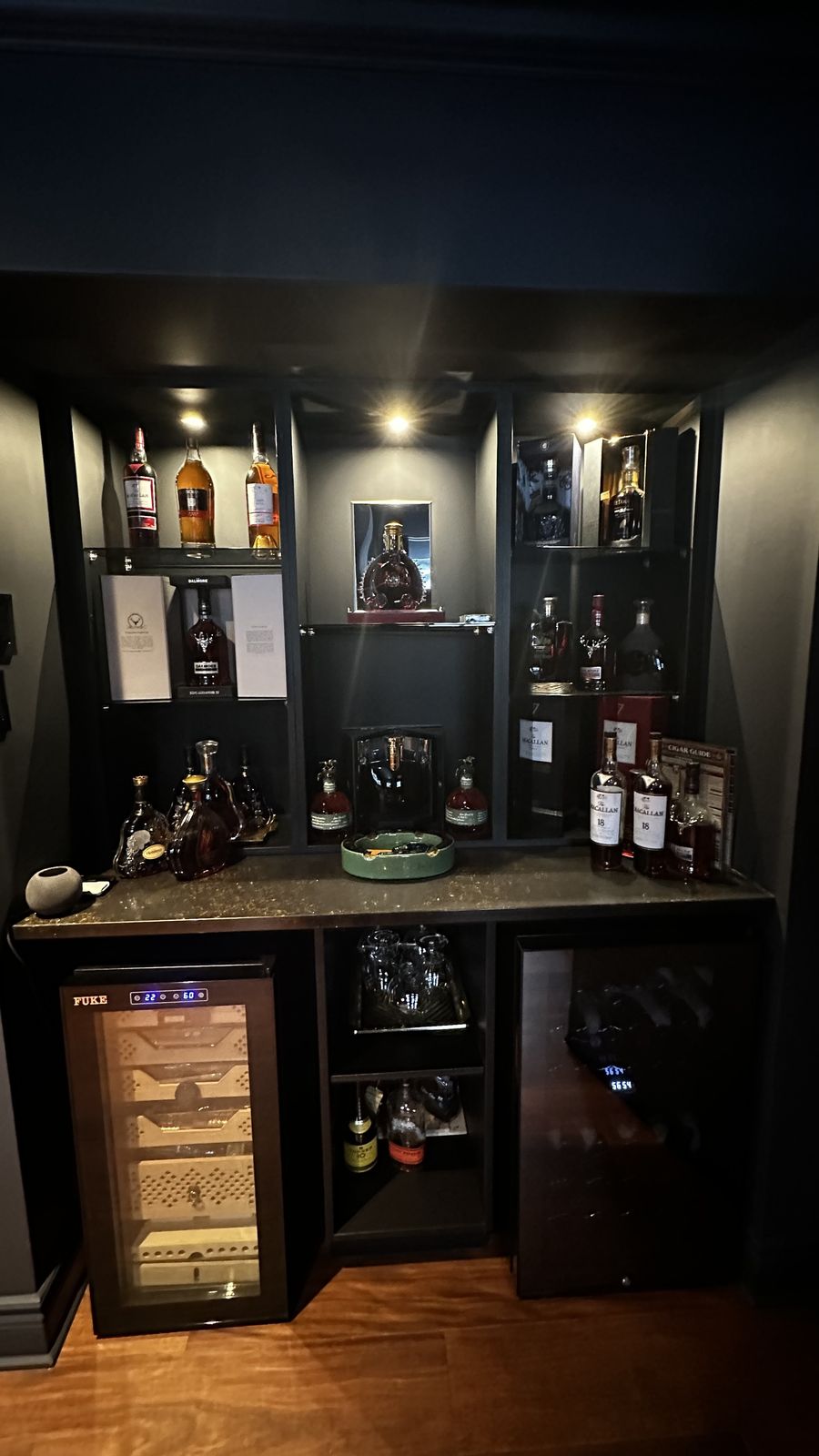Accent lighting and spotlights over a built-in bar cabinet in a dark, refined room