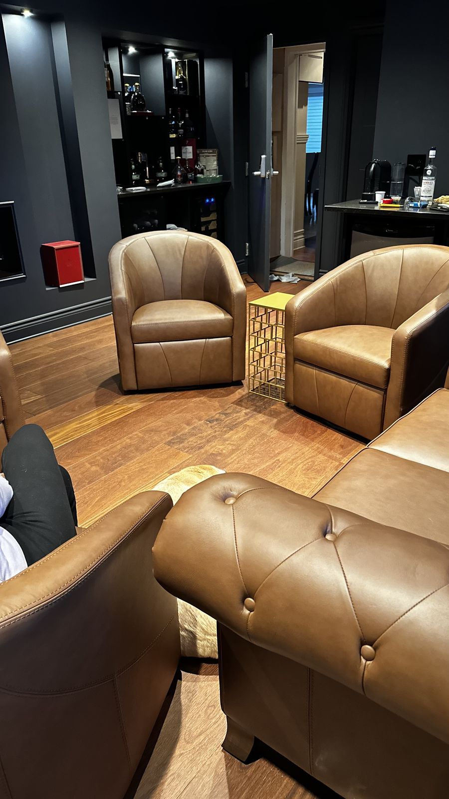 Un salon rénové avec murs foncés, plancher de bois franc et éclairage encastré