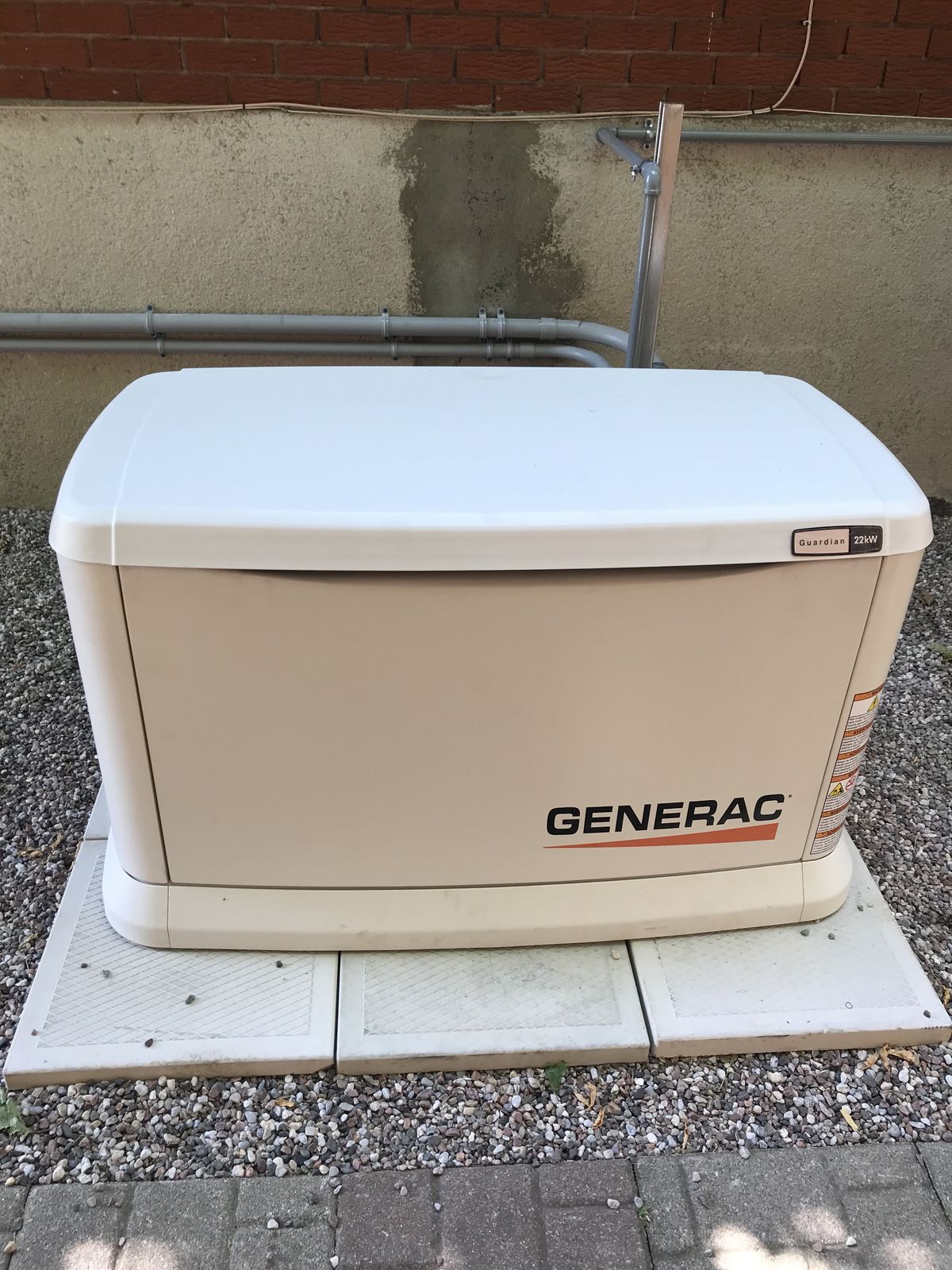 A standby generator installed on a paving-stone pad beside a home